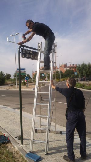 Dos operarios colocan la placa con el nombre de Carlos Llamas en una glorieta en Canillejas. Dos operarios colocan la placa con el nombre de Carlos Llamas en una glorieta en Canillejas.