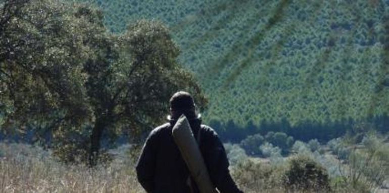 Un cazador, escopeta al hombro enfundada Un cazador, escopeta al hombro enfundada