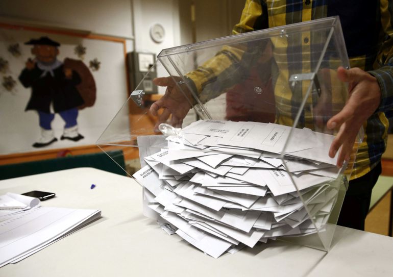 El presidente de una mesa electoral deposita los votos de la urna sobre una mesa El presidente de una mesa electoral deposita los votos de la urna sobre una mesa