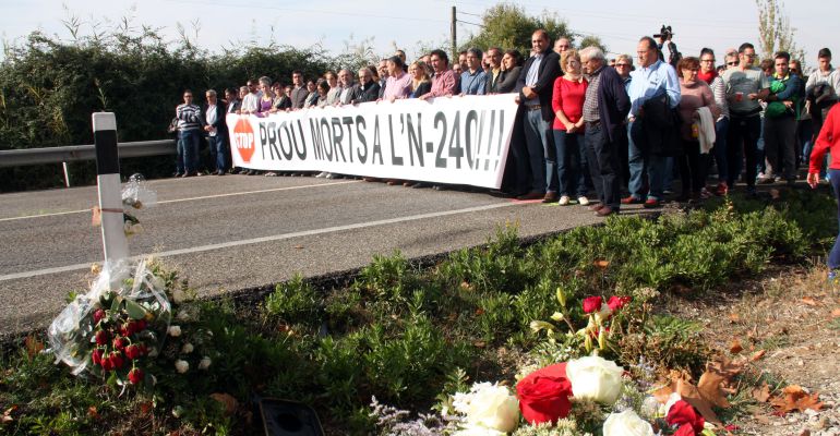 Imatge dels concentrats tallant la carretera N-240 al punt de l'últim accident mortal amb rams de flors en primer terme. Imatge dels concentrats tallant la carretera N-240 al punt de l'últim accident mortal amb rams de flors en primer terme.