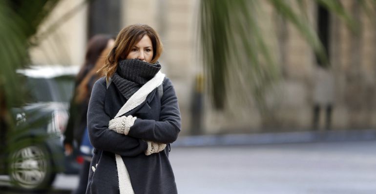Una mujer buien abrigada pasea por el centro de la ciudad Una mujer buien abrigada pasea por el centro de la ciudad
