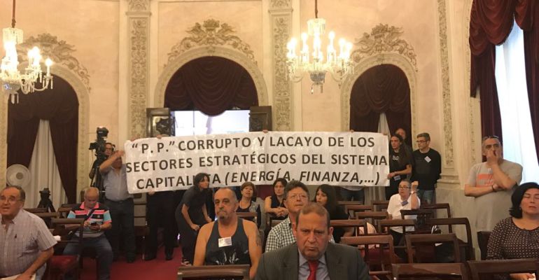 Un grupo de asistentes despliegan una pancarta contra el PP en plena sesión Un grupo de asistentes despliegan una pancarta contra el PP en plena sesión
