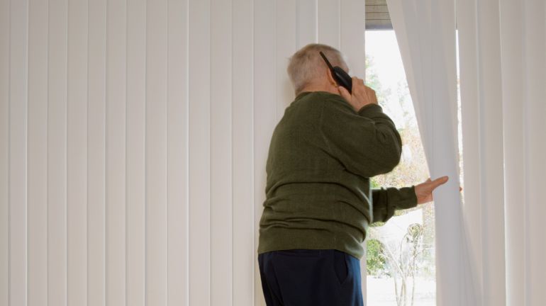 Un anciano mirando por la ventana de su casa Un anciano mirando por la ventana de su casa