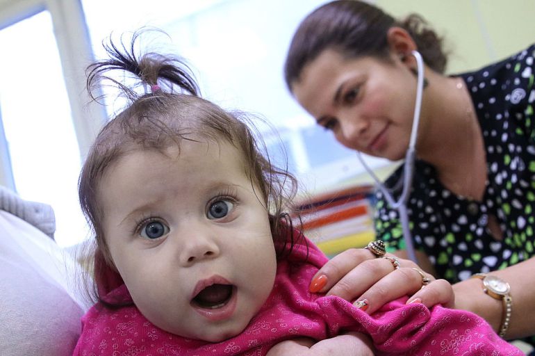 Un pediatra consulta la salud de una niña Un pediatra consulta la salud de una niña