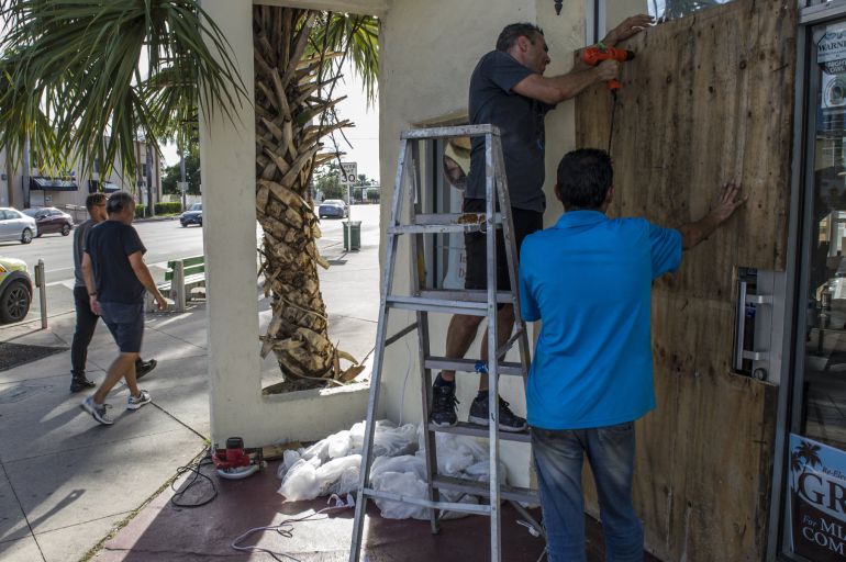 Dos hombres aseguran las puertas y ventanas de su negocio Dolci di Sicilia, ubicado en Miami Dos hombres aseguran las puertas y ventanas de su negocio Dolci di Sicilia, ubicado en Miami