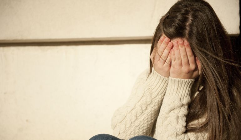 Una joven se cubre el rostro, víctima de acoso escolar. Una joven se cubre el rostro, víctima de acoso escolar.
