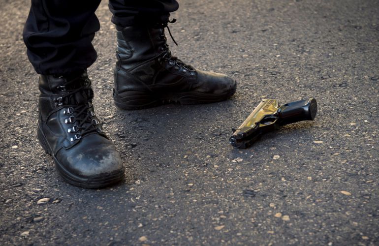 Un policía custodia la pistola, sobre el asfalto, con la que esta mañana un hombre ha entrado en la sucursal de Bankia del distrito madrileño de Usera Un policía custodia la pistola, sobre el asfalto, con la que esta mañana un hombre ha entrado en la sucursal de Bankia del distrito madrileño de Usera