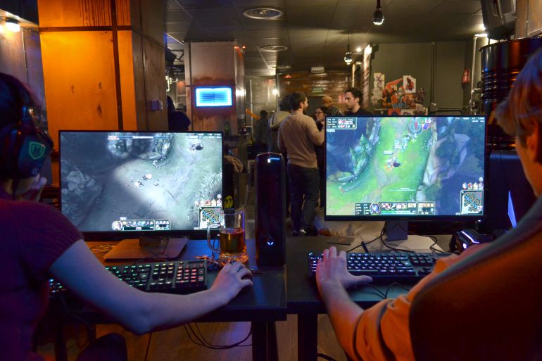 Dos clientes de un bar de esports juegan una partida mientras toman una cerveza. Dos clientes de un bar de esports juegan una partida mientras toman una cerveza.