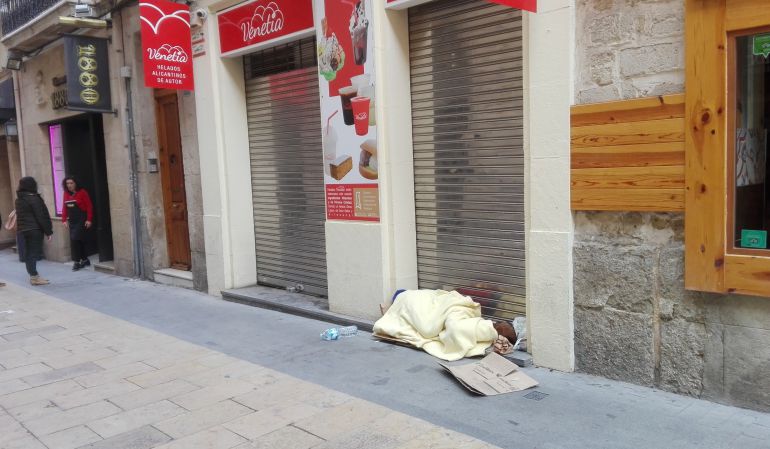 Una persona sin hogar duerme cobijado en un establecimiento en pleno centro de Alicante. Una persona sin hogar duerme cobijado en un establecimiento en pleno centro de Alicante.