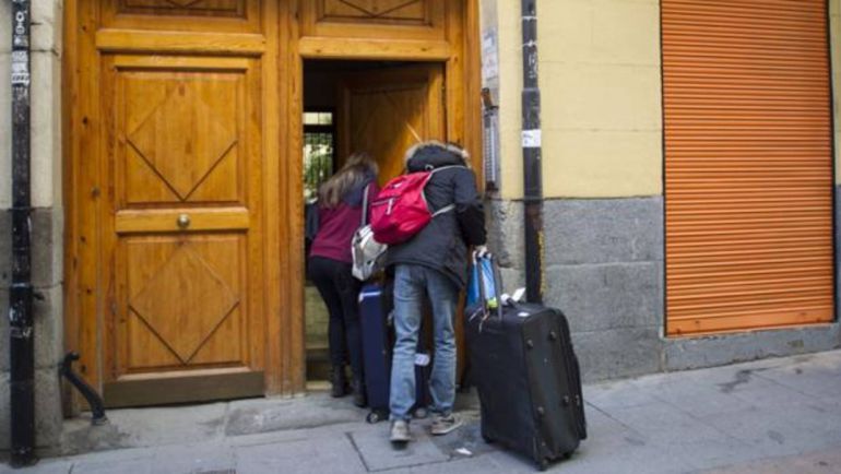 Unos turistas accediendo a un portal para alojarse en una vivienda turística Unos turistas accediendo a un portal para alojarse en una vivienda turística