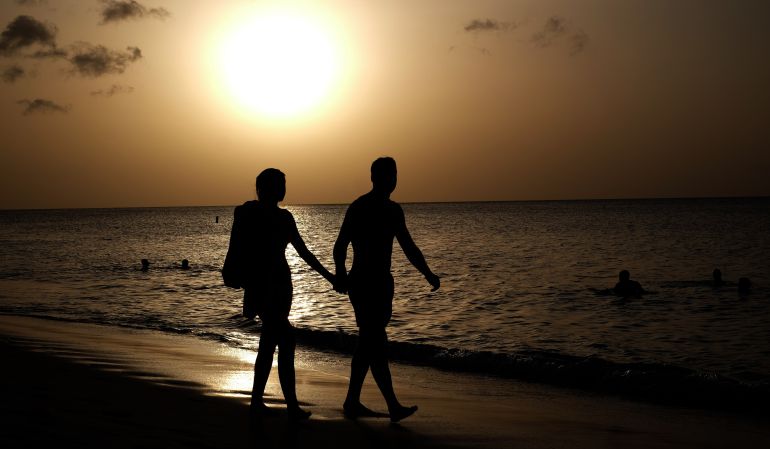 Una pareja camina por una playa Una pareja camina por una playa
