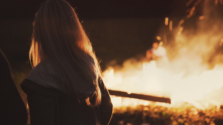 Una mujer observa una de las hogueras de la noche san Juan.