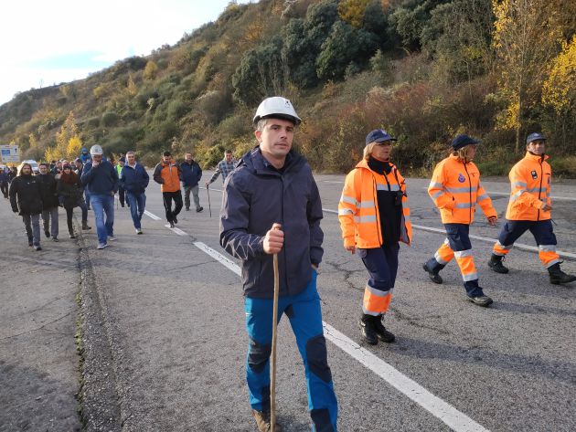 Un minero camina, seguido por sus compañeros Un minero camina, seguido por sus compañeros