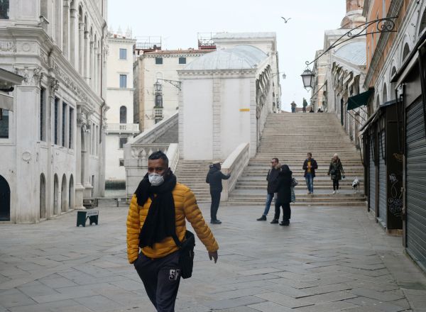 A man wearing a protective face mask walks through a street after the Italian government imposed a virtual lockdown on the north of Italy including Venice to try to contain a coronavirus outbreak, in Venice, Italy, March 9, 2020. REUTERS/Manuel Silvestri