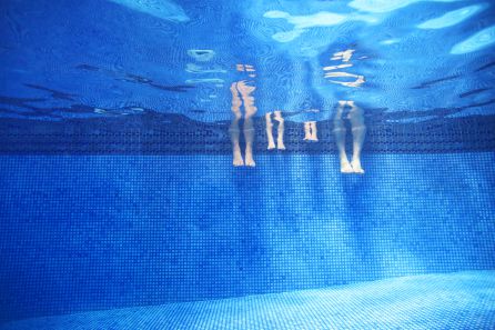 Los pies de unos bañistas desde el interior de una piscina Los pies de unos bañistas desde el interior de una piscina