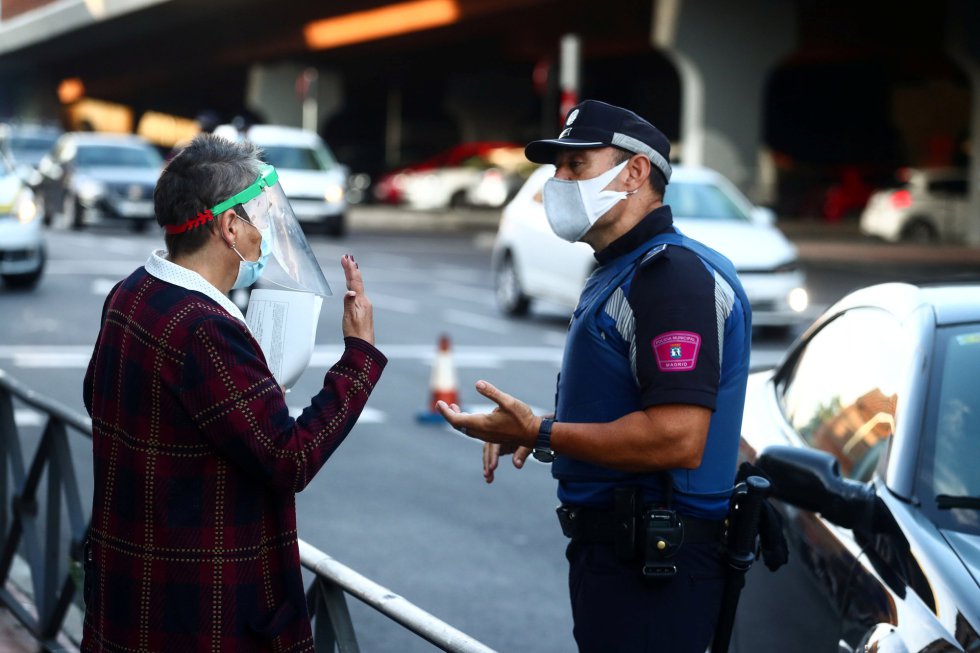 Un policía local habla con una mujer, vecina de Vallecas, una de las zonas de confinamiento selectivo. Un policía local habla con una mujer, vecina de Vallecas, una de las zonas de confinamiento selectivo.