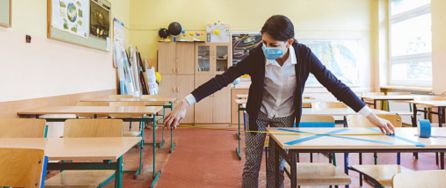 Docente midiendo la distancia entre pupitres en un aula escolar Docente midiendo la distancia entre pupitres en un aula escolar