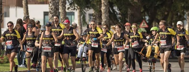 Un nutrido grupo de voluntarios en una carrera con sus dos sillas de ruedas Un nutrido grupo de voluntarios en una carrera con sus dos sillas de ruedas