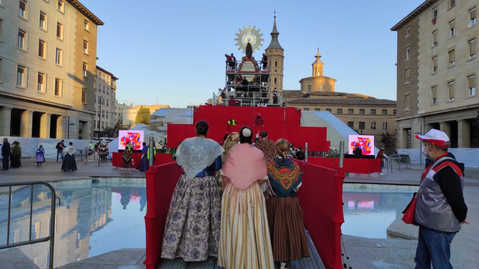 Los oferentes cruzando la pasarela que salva el agua de la fuente de la Hispanidad en la plaza del Pilar. Los oferentes cruzando la pasarela que salva el agua de la fuente de la Hispanidad en la plaza del Pilar.