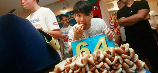 Un joven comiendo perritos calientes Un joven comiendo perritos calientes