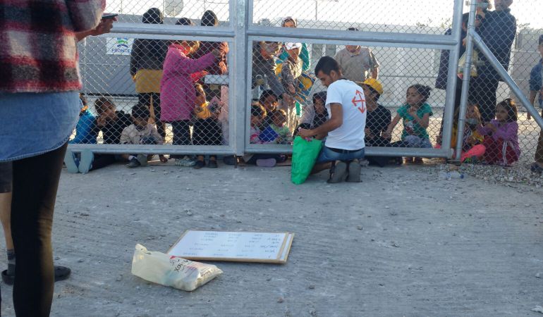 Un voluntario da clases de inglés, separado por una valla, a niños retenidos en el campamento de Moria, en la isla de Lesbos Un voluntario da clases de inglés, separado por una valla, a niños retenidos en el campamento de Moria, en la isla de Lesbos