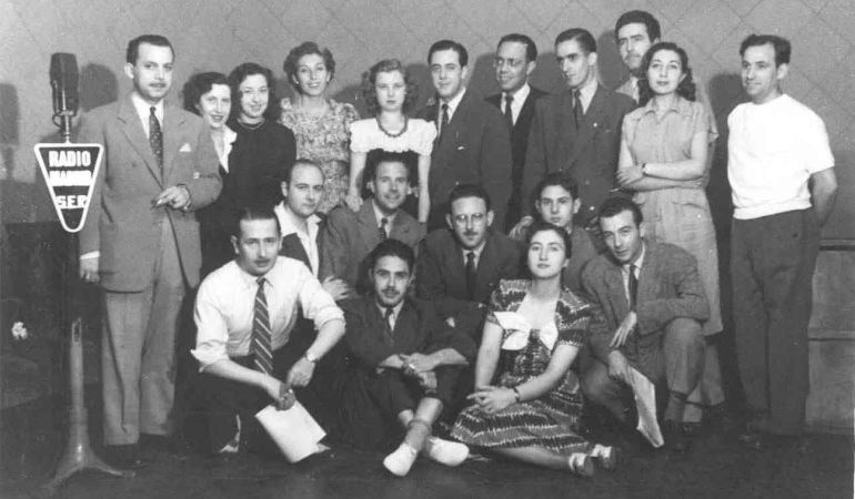Guillermo Sautier Casaseca, de rodillas con camisa blanca y corbata, acompañado por el cuadro de actores de Radio Madrid tras una grabación. Guillermo Sautier Casaseca, de rodillas con camisa blanca y corbata, acompañado por el cuadro de actores de Radio Madrid tras una grabación.