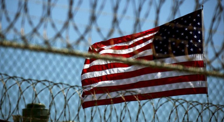 La bandera estadounidense ondea tras los alambres de seguridad en una estación naval en Guantánamo. La bandera estadounidense ondea tras los alambres de seguridad en una estación naval en Guantánamo.