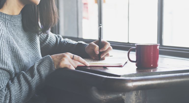 Imagen de una chica escribiendo junto a un ventanal. Imagen de una chica escribiendo junto a un ventanal.