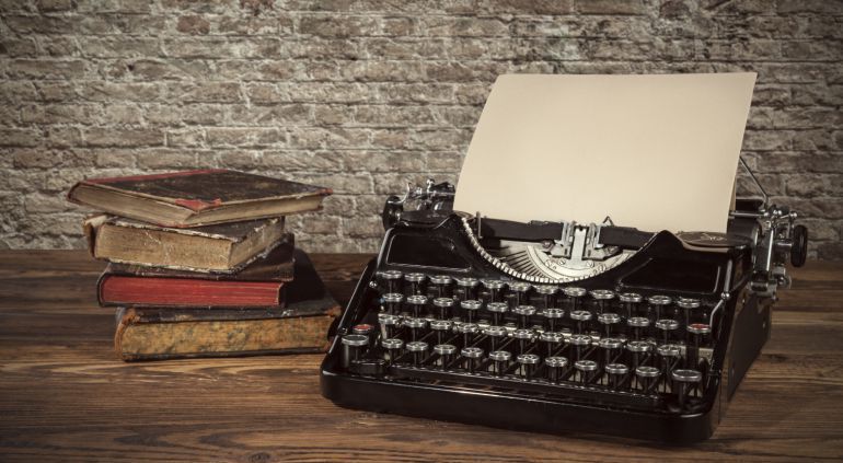 Imagen de una máquina de escribir junto a unos libros antiguos sobre una mesa. Imagen de una máquina de escribir junto a unos libros antiguos sobre una mesa.