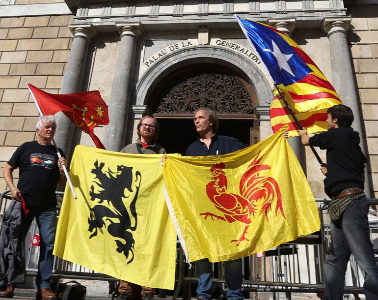 Cuatro personas sostienen las banderas (de izda a dcha) de las regiones de Occitania, Flandes, Valonia y la estelada, ante el Palau de la Generalitat, en el primer día laborable tras la puesta en marcha del artículo 155 de la Constitución para hacer frente al desafío secesionista en Cataluña. Cuatro personas sostienen las banderas (de izda a dcha) de las regiones de Occitania, Flandes, Valonia y la estelada, ante el Palau de la Generalitat, en el primer día laborable tras la puesta en marcha del artículo 155 de la Constitución para hacer frente al desafío secesionista en Cataluña.