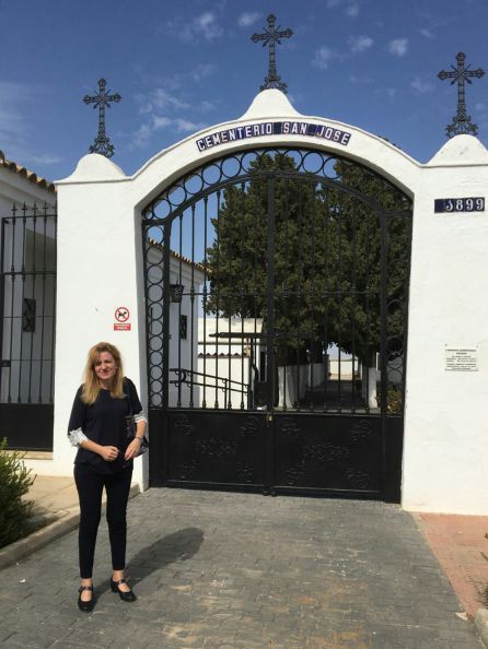 Mari Carmen frente a las rejas negras que dan entrada al cementerio de La Puebla de Cazalla (Sevilla).