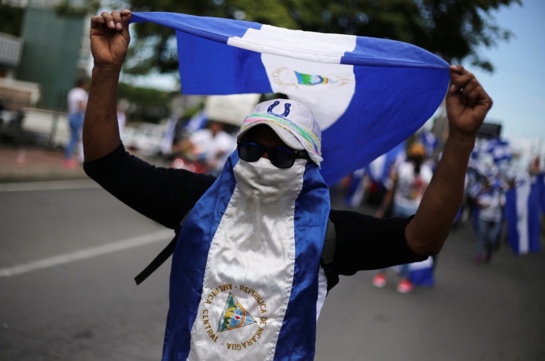 Un hombre camuflado con la bandera de Nicaragua y gafas de sol durante una de las manifestaciones en contra del Gobierno de Daniel Ortega Un hombre camuflado con la bandera de Nicaragua y gafas de sol durante una de las manifestaciones en contra del Gobierno de Daniel Ortega