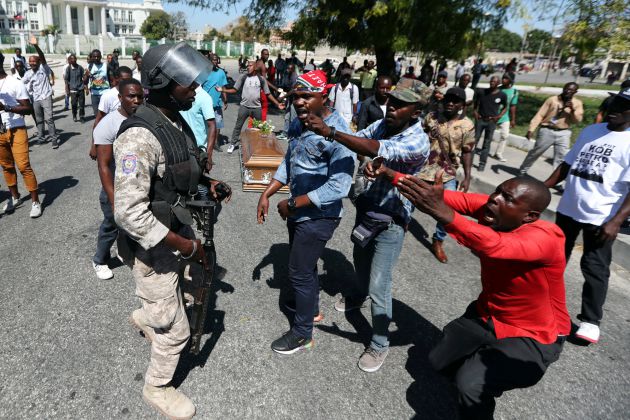 Local residents argue with a policeman while the casket of a man shot dead during anti-government protests lies on the ground in Port-au-Prince, Haiti, February 22, 2019 Local residents argue with a policeman while the casket of a man shot dead during anti-government protests lies on the ground in Port-au-Prince, Haiti, February 22, 2019