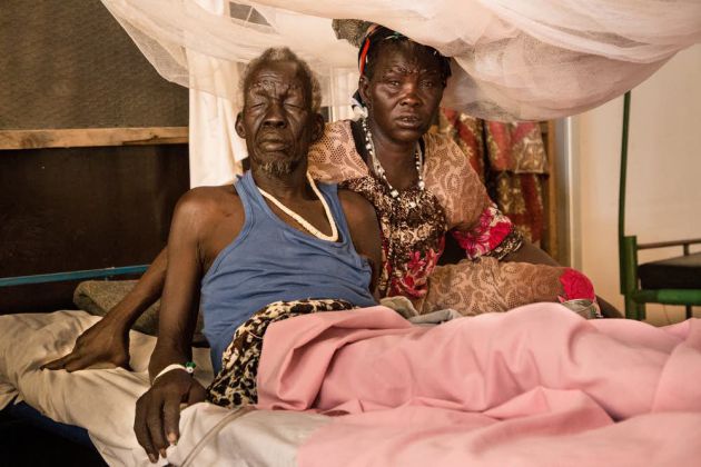 Una mujer se sienta junto a su marido, un paciente del hospital de MSF en el centro de protección civil de Malakal, en Sudán del Sur. Marzo 2019 Una mujer se sienta junto a su marido, un paciente del hospital de MSF en el centro de protección civil de Malakal, en Sudán del Sur. Marzo 2019