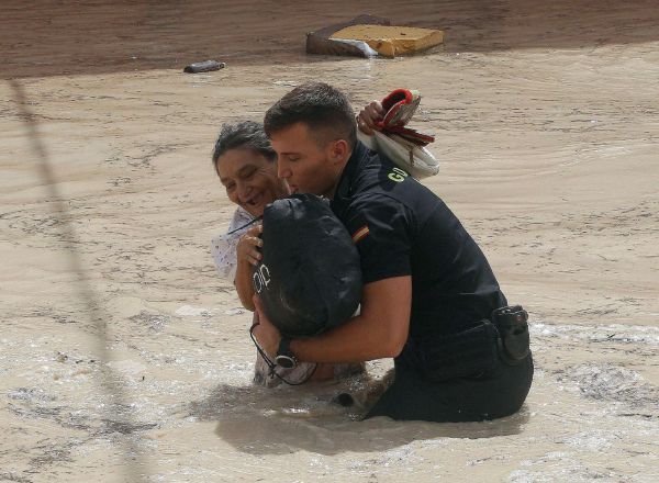 Un policia ayuda a una vecina de Almoradí tras inundarse las calles de la población por la rotura del dique del cauce del río Segura tras el paso de la Gota Fría.