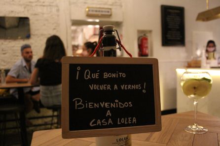 Un cartel da la bienvenida a los clientes de Casa Lolea. Al lado vemos una sangría hecha con vino blanco, una de sus cinco variedades. Un cartel da la bienvenida a los clientes de Casa Lolea. Al lado vemos una sangría hecha con vino blanco, una de sus cinco variedades.