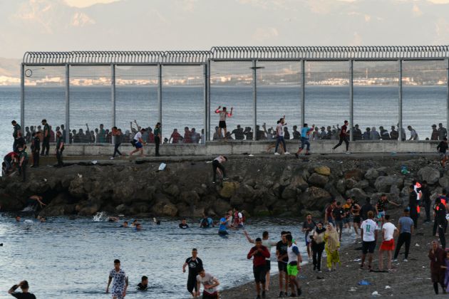 Personas migrantes caminan por la playa del Tarajal. Personas migrantes caminan por la playa del Tarajal.