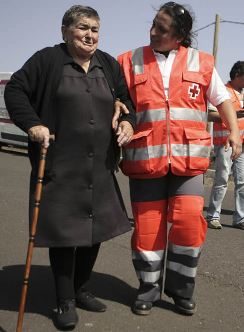 Una vecina de La Restinga, en la isla de El Hierro, es acompañada por un miembro de Cruz Roja durante la evacuación de la localidad Una vecina de La Restinga, en la isla de El Hierro, es acompañada por un miembro de Cruz Roja durante la evacuación de la localidad