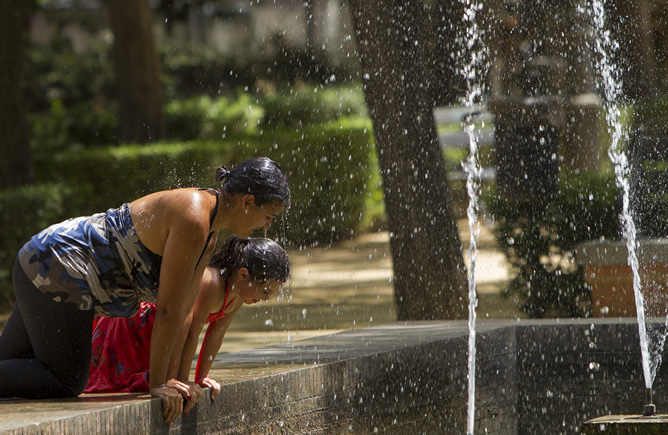Dos jóvenes se refrescan en una fuente en Sevilla en un día de fuerte calor Dos jóvenes se refrescan en una fuente en Sevilla en un día de fuerte calor