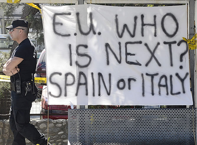 Un policía camina junto a una pancarta en la que se puede leer 'Unión Europea, ¿Quién es el siguiente? España o Italia' frente al Parlamento en Nicosia Un policía camina junto a una pancarta en la que se puede leer 'Unión Europea, ¿Quién es el siguiente? España o Italia' frente al Parlamento en Nicosia