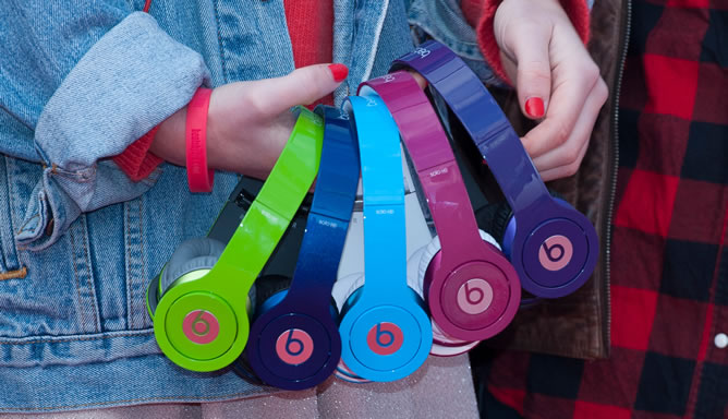 Una joven sostiene varios auriculares Beats Una joven sostiene varios auriculares Beats