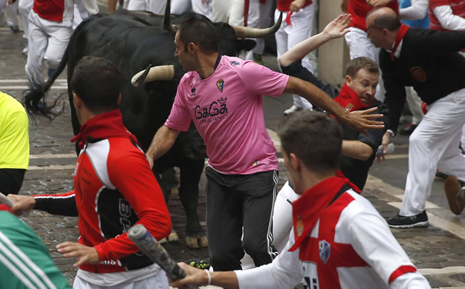 Varios mozos corren delante de los toros de la ganadería de Victoriano del Río Cortés en la calle Mercaderes con la calle Estafeta, durante el tercer encierro de los sanfermines 2014. Varios mozos corren delante de los toros de la ganadería de Victoriano del Río Cortés en la calle Mercaderes con la calle Estafeta, durante el tercer encierro de los sanfermines 2014.