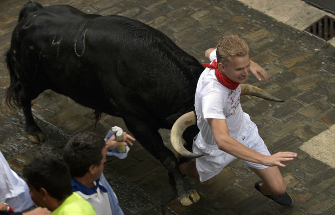 Un corredor es atrapado entre los cuernos de un toro de la ganadería Fuente Ymbro en la calle Santo Domingo Un corredor es atrapado entre los cuernos de un toro de la ganadería Fuente Ymbro en la calle Santo Domingo
