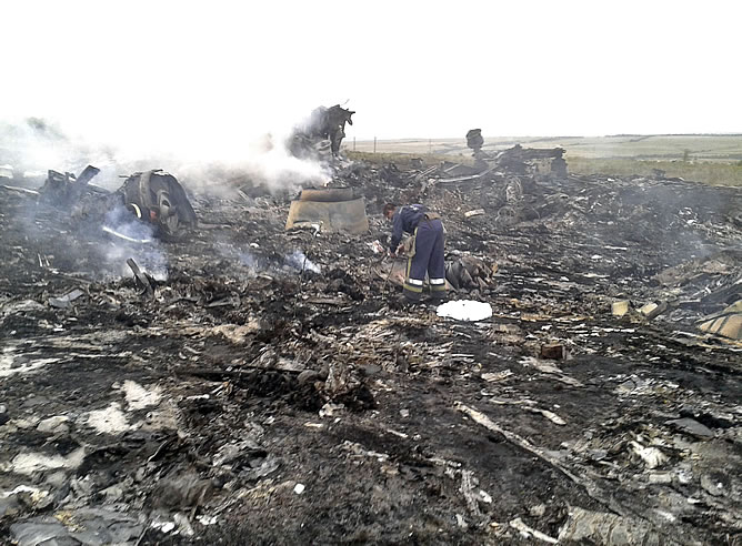 Miembros de Emergencias trabajan junto a los restos del avión malasio. Miembros de Emergencias trabajan junto a los restos del avión malasio.