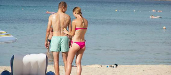 Dos bañistas se ponen crema solar en una playa del Mediterráneo durante la temporada estival Dos bañistas se ponen crema solar en una playa del Mediterráneo durante la temporada estival