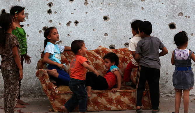 Niños palestinos juegan en un sofá, junto a un muro baleado en el barrio de Al Shejaeiya al este de la ciudad de Gaza Niños palestinos juegan en un sofá, junto a un muro baleado en el barrio de Al Shejaeiya al este de la ciudad de Gaza