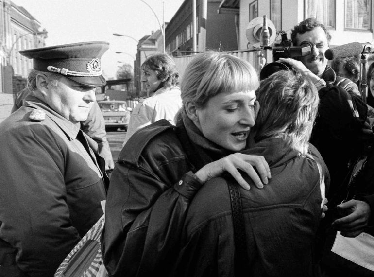 Un ciudadano de Berlin Este abraza a una mujer del Oeste bajo la mirada te un guardia de frontera en el checkpoint de Invalidenstrasse al día siguiente de la caída del Muro Un ciudadano de Berlin Este abraza a una mujer del Oeste bajo la mirada te un guardia de frontera en el checkpoint de Invalidenstrasse al día siguiente de la caída del Muro