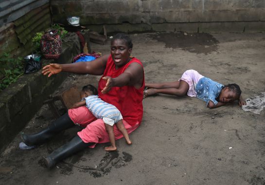 MONROVIA, LIBERIA - OCTOBER 10: Sophia Doe sits with her grandchildren Beauty Mandi, 9 months (L) and Arthuneh Qunoh, 9, (R), while watching the arrival an Ebola burial team to take away the body of her daughter Mekie Nagbe, 28, for cremation on October 10, 2014 in Monrovia, Liberia. The children seen in the photo are daughters of the deceased. Mekie Nagbe, a market vendor died outside her home earlier in the morning while trying to walk to a treatment center, according to her relatives. The burial of loved ones is important in Liberian culture, making the removal of infected bodies for cremation all the more traumatic for surviving family members. The World Health Organization says the Ebola epidemic has now killed more than 4,000 people in West Africa.The woman had died outside her home earlier in the morning while trying to walk to a treatment center, according to her relatives. The burial of loved ones is important in Liberian culture, making the removal of infected bodies for cremation all the more traumatic for surviving family members. (Photo by John Moore/Getty Images) *** BESTOF2014 *** YEARINREVIEW *** MONROVIA, LIBERIA - OCTOBER 10: Sophia Doe sits with her grandchildren Beauty Mandi, 9 months (L) and Arthuneh Qunoh, 9, (R), while watching the arrival an Ebola burial team to take away the body of her daughter Mekie Nagbe, 28, for cremation on October 10, 2014 in Monrovia, Liberia. The children seen in the photo are daughters of the deceased. Mekie Nagbe, a market vendor died outside her home earlier in the morning while trying to walk to a treatment center, according to her relatives. The burial of loved ones is important in Liberian culture, making the removal of infected bodies for cremation all the more traumatic for surviving family members. The World Health Organization says the Ebola epidemic has now killed more than 4,000 people in West Africa.The woman had died outside her home earlier in the morning while trying to walk to a treatment center, according to her relatives. The burial of loved ones is important in Liberian culture, making the removal of infected bodies for cremation all the more traumatic for surviving family members. (Photo by John Moore/Getty Images) *** BESTOF2014 *** YEARINREVIEW ***