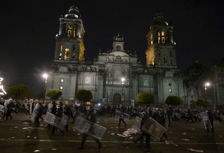 Miembros de la policia federal mexicana toman posiciones durante los enfrentamientos con los manifestantes frente al palacio nacional en la Plaza del Zocalo, sede de la presidencia de la República Miembros de la policia federal mexicana toman posiciones durante los enfrentamientos con los manifestantes frente al palacio nacional en la Plaza del Zocalo, sede de la presidencia de la República
