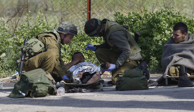 Un soldado isrelí herido recibe atención médica de varios compañeros después de que impactara un misil antitanques en su vehículo en la frontera entre Israel y el Líbano. Un soldado isrelí herido recibe atención médica de varios compañeros después de que impactara un misil antitanques en su vehículo en la frontera entre Israel y el Líbano.
